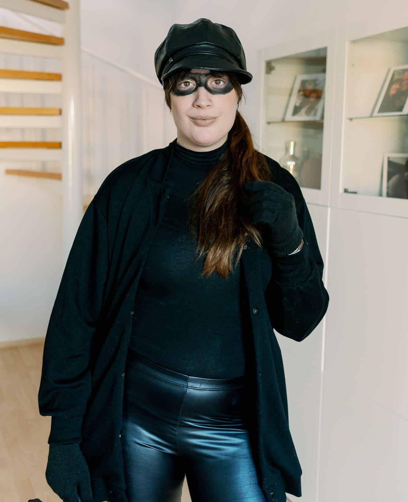 Frau in Einbrecher-Kostüm mit schwarzer Schminke um die Augen