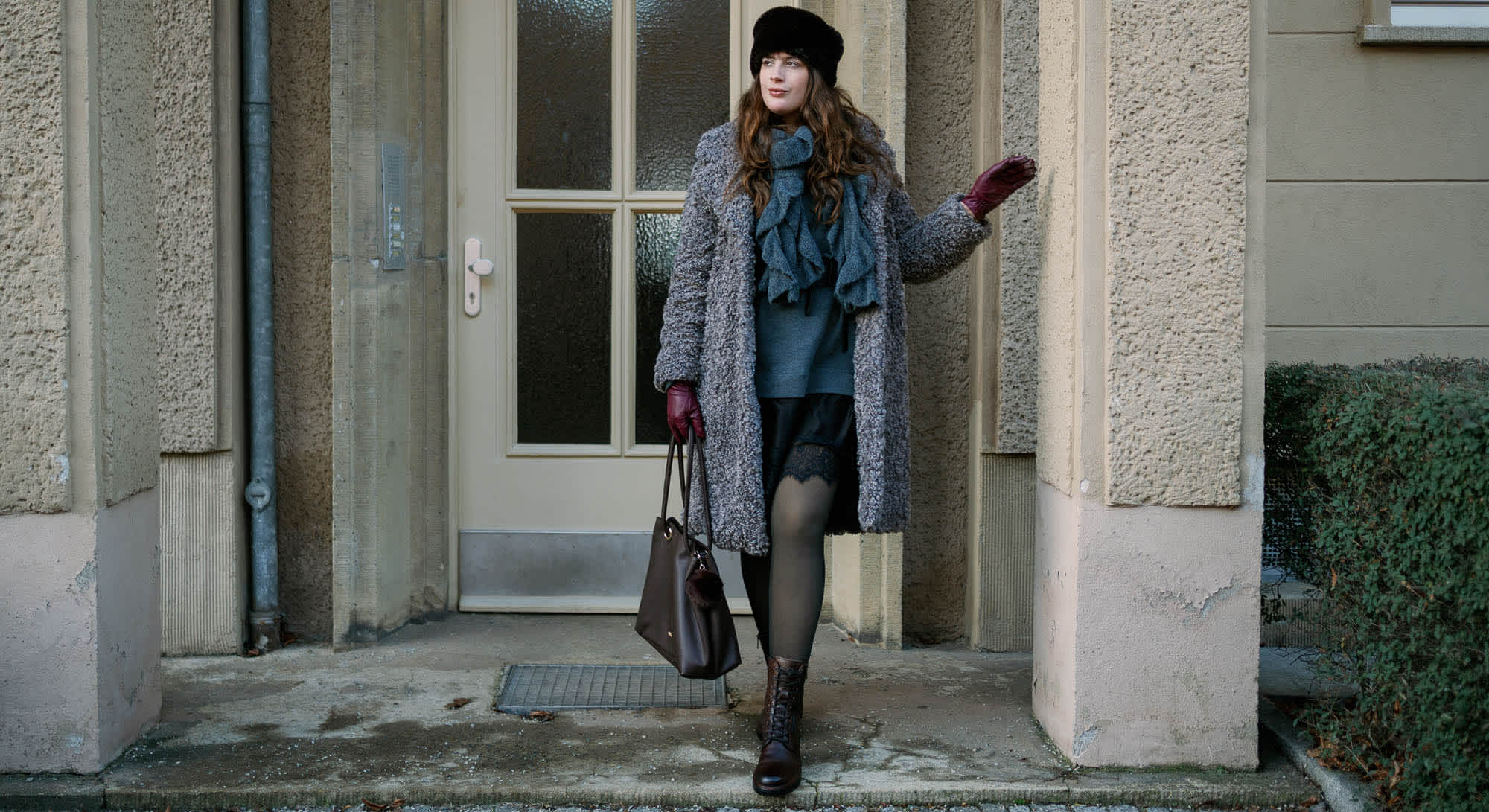 Frau in kuscheligem Wollmantel, stehend in Hauseingang