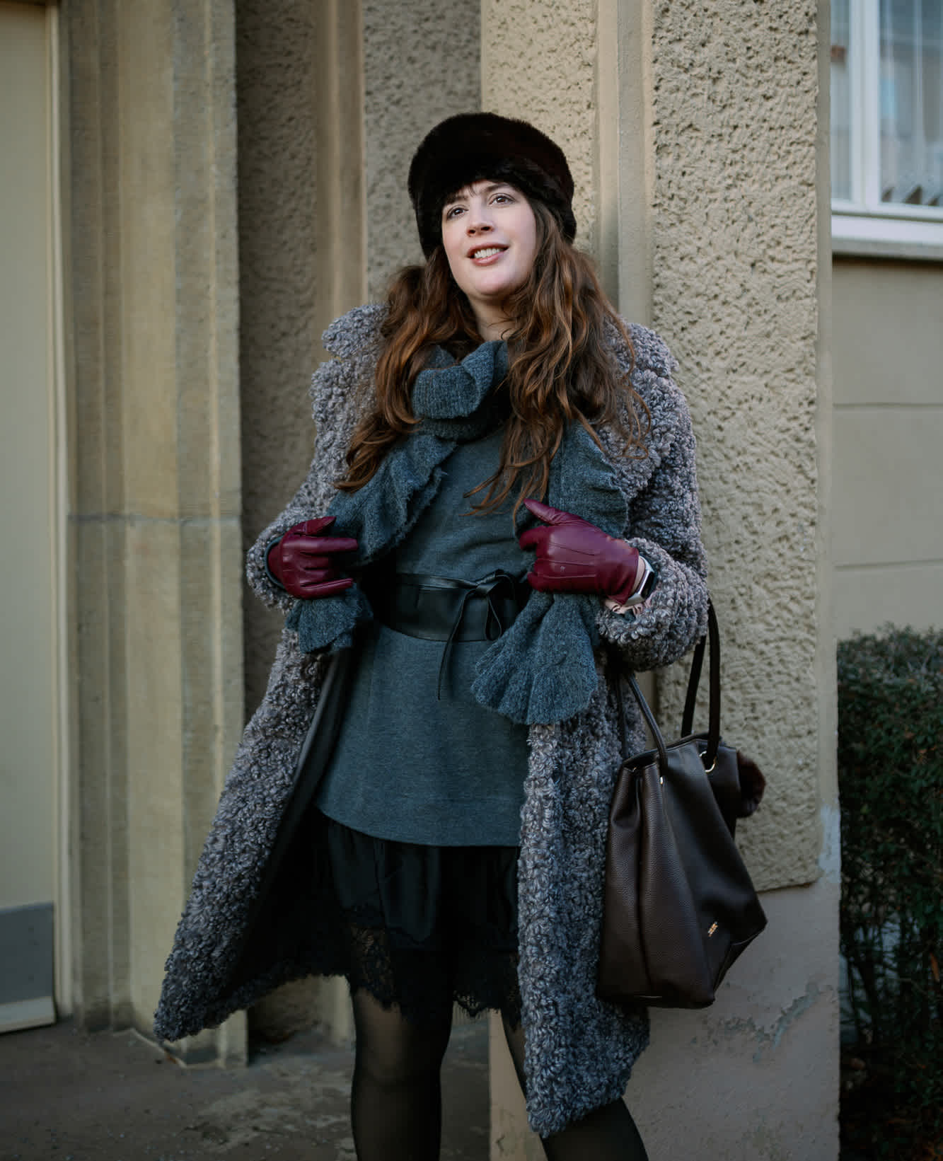 Frau trägt grauen Fake Fur-Mantel, kombiniert mit Strick-Pullover, schwarzer Mütze und roten Handschuhen