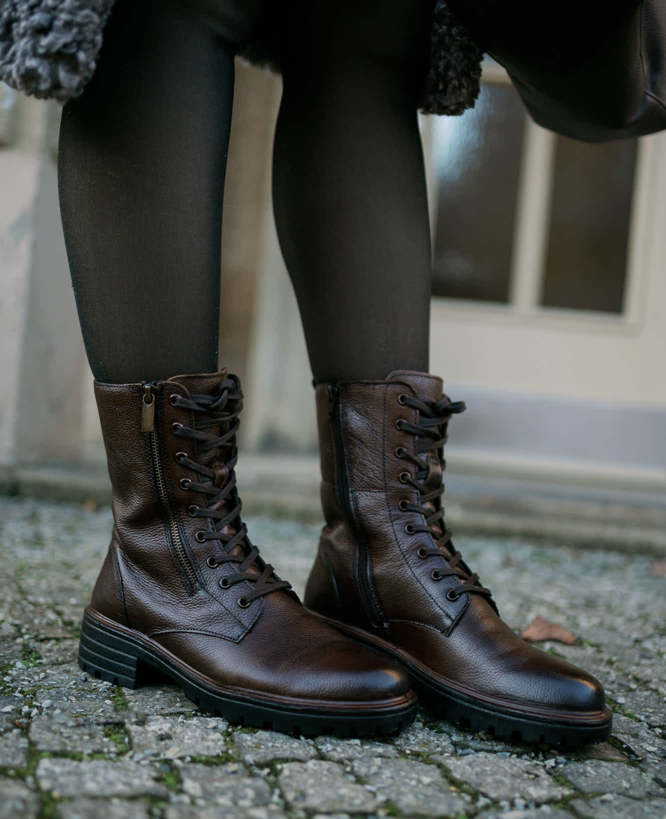 Frau trägt schwarze Lack-Boots, stehend auf Gehweg