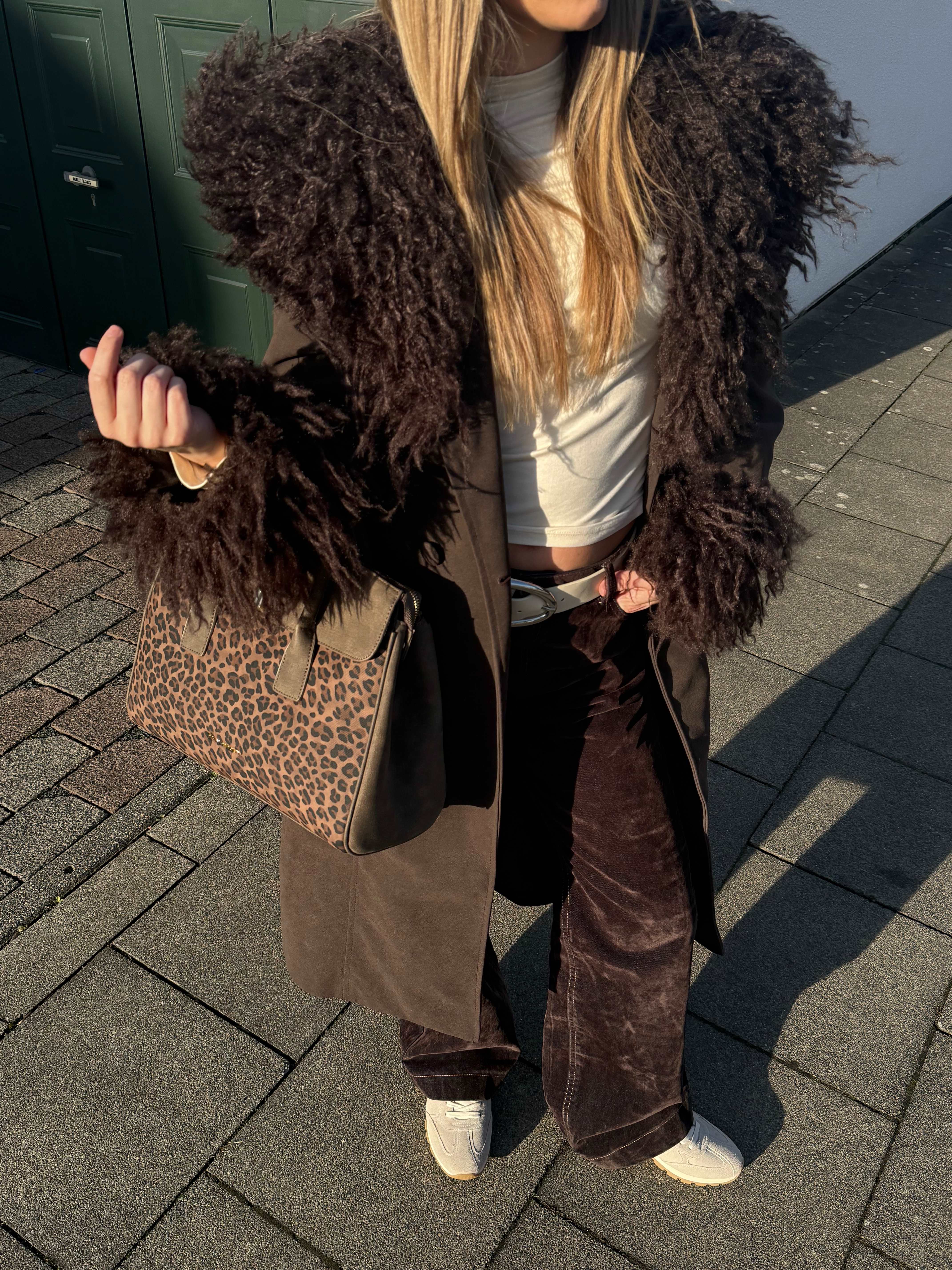 Top-Down-Ansicht einer jungen Frau mit weißem Top, Felljacke und Animal Print-Handtasche