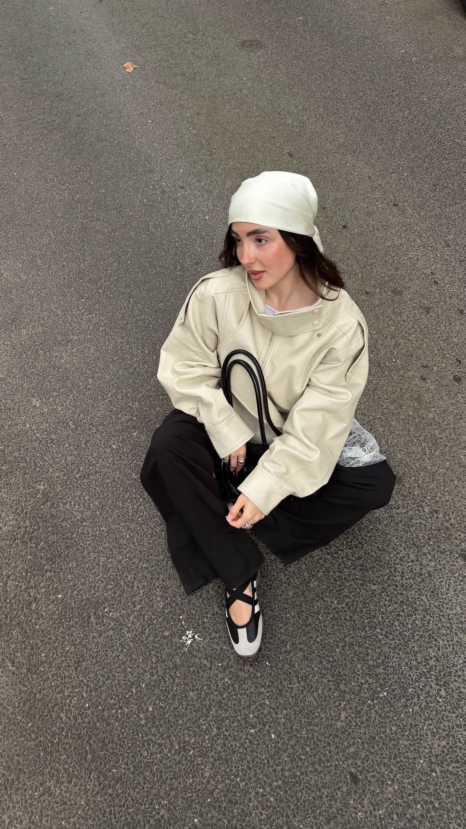 Fokus auf schwarz-weißen Ballerina-Sneakern mit Riemchen. Dazu cremefarbene Lederjacke, schwarze Hose, Kopftuch und Mesh-Lagenlook.