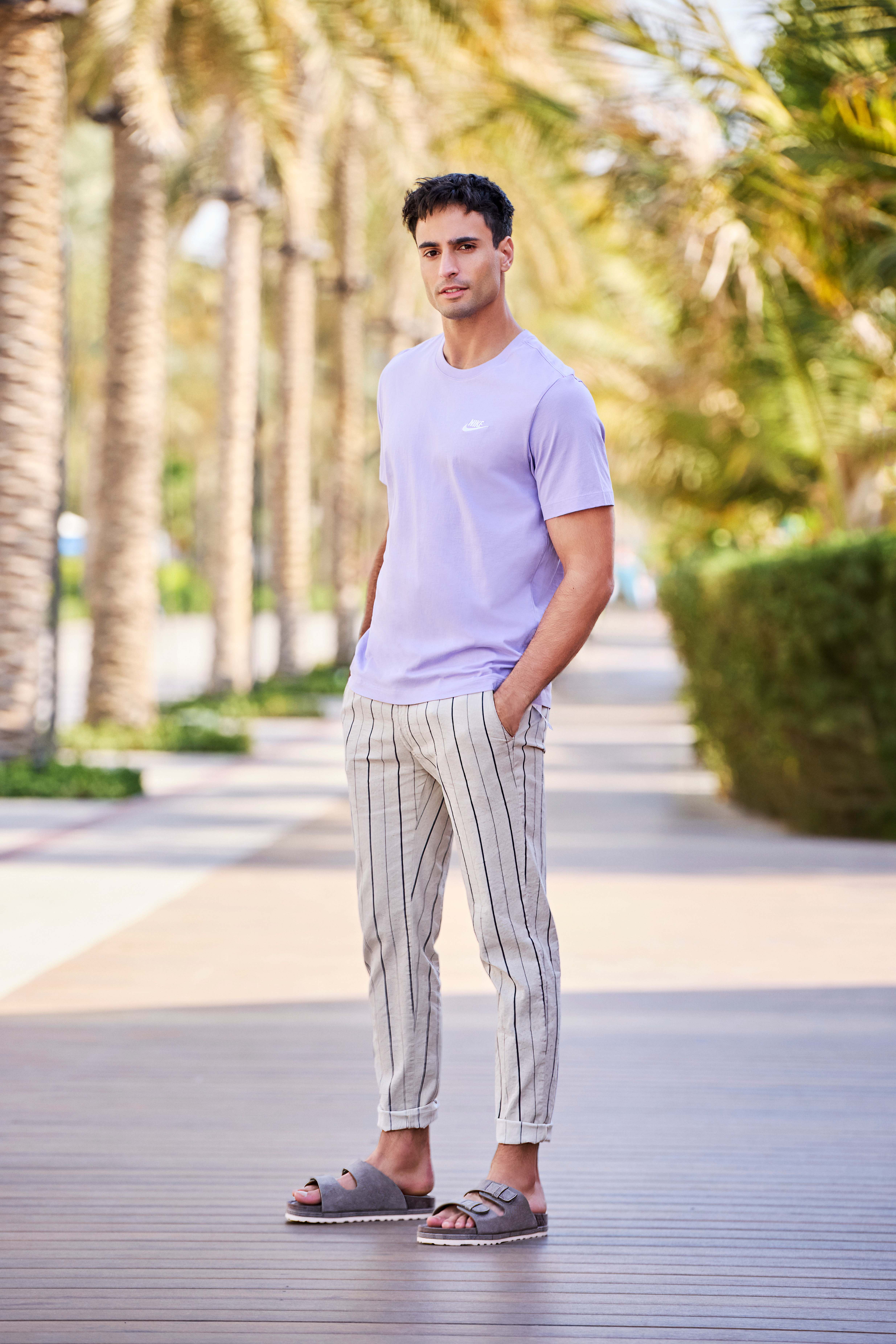 Mann in Casual-Outfit mit Shirt, gestreifter Chinohose und bequemen Pantoletten