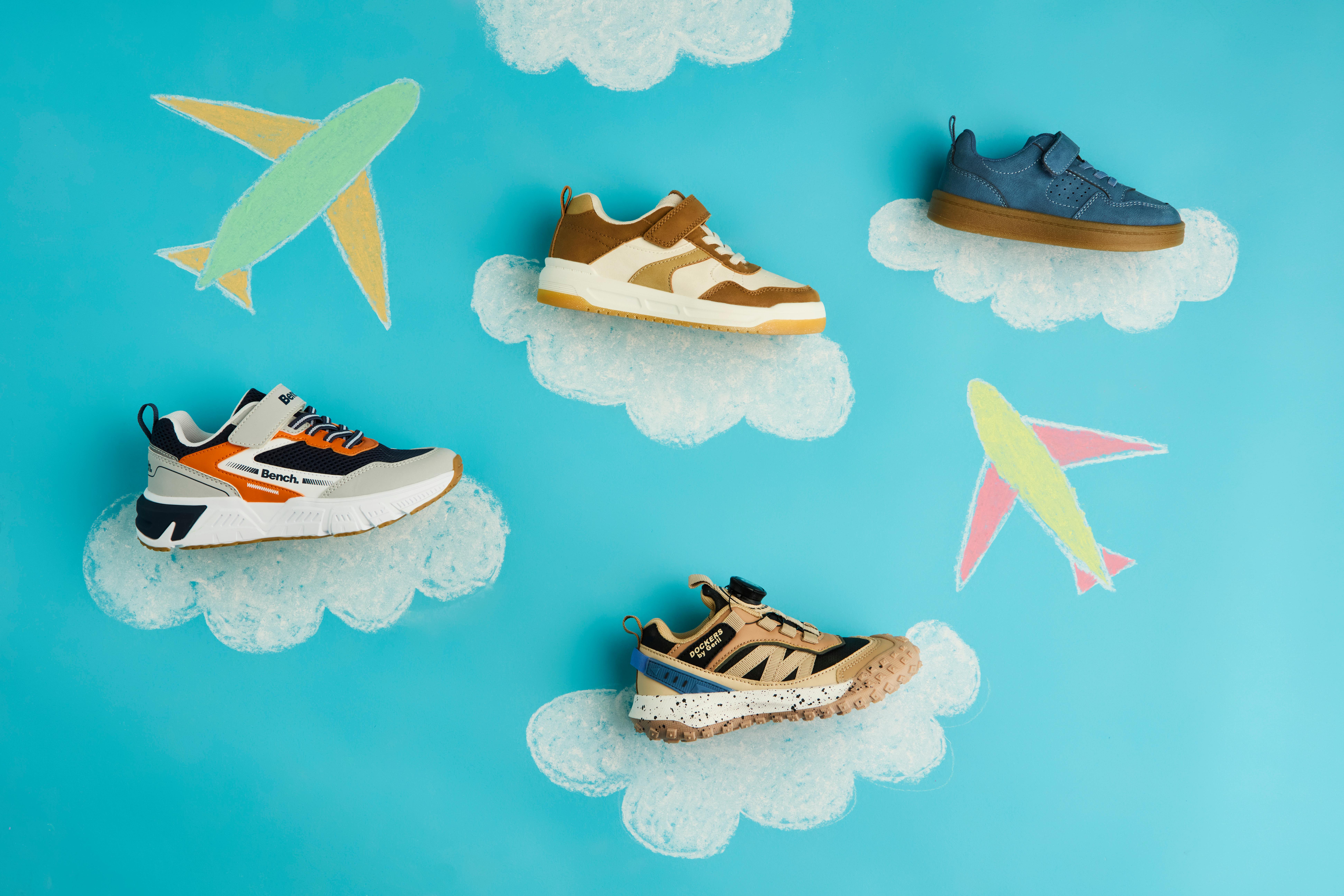 Vier bunte Kinderschuhe liegen auf stilisierten Wolken