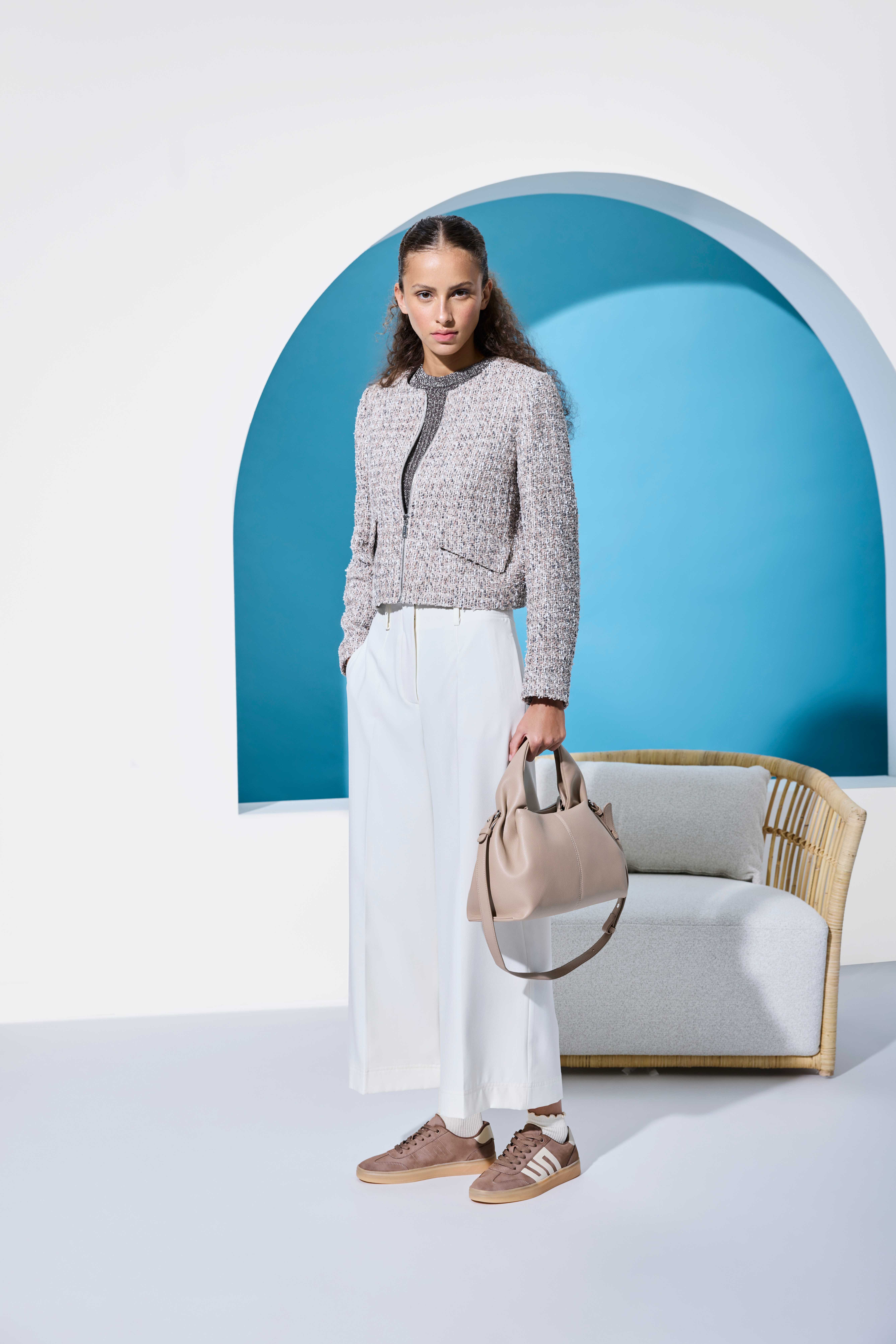 Frau in grauem Top mit weißer Culotte, dazu Handtasche und Sneaker-Schuhe