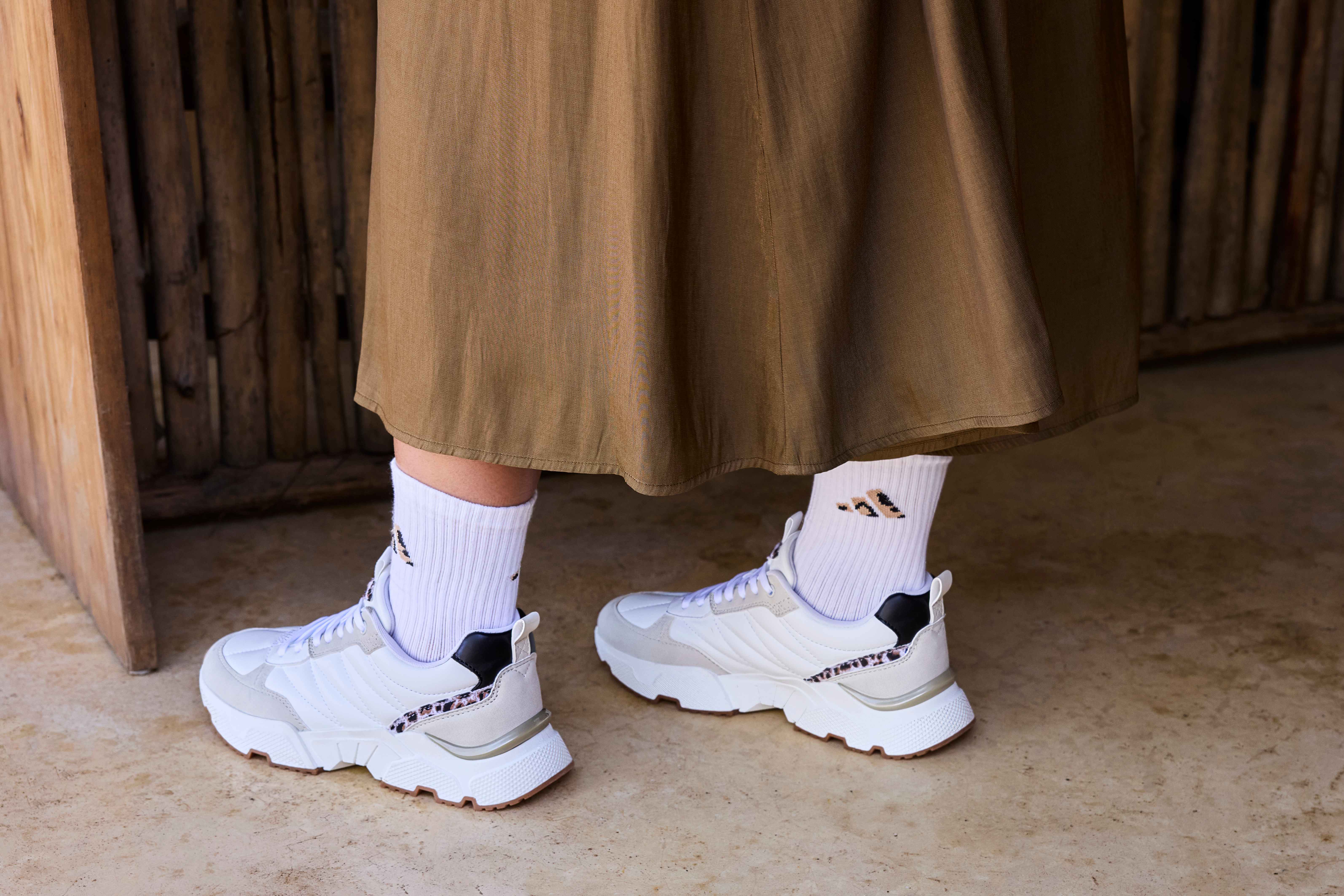 Frau trägt weiße Strümpfe in Kombination mit passenden Sneakern