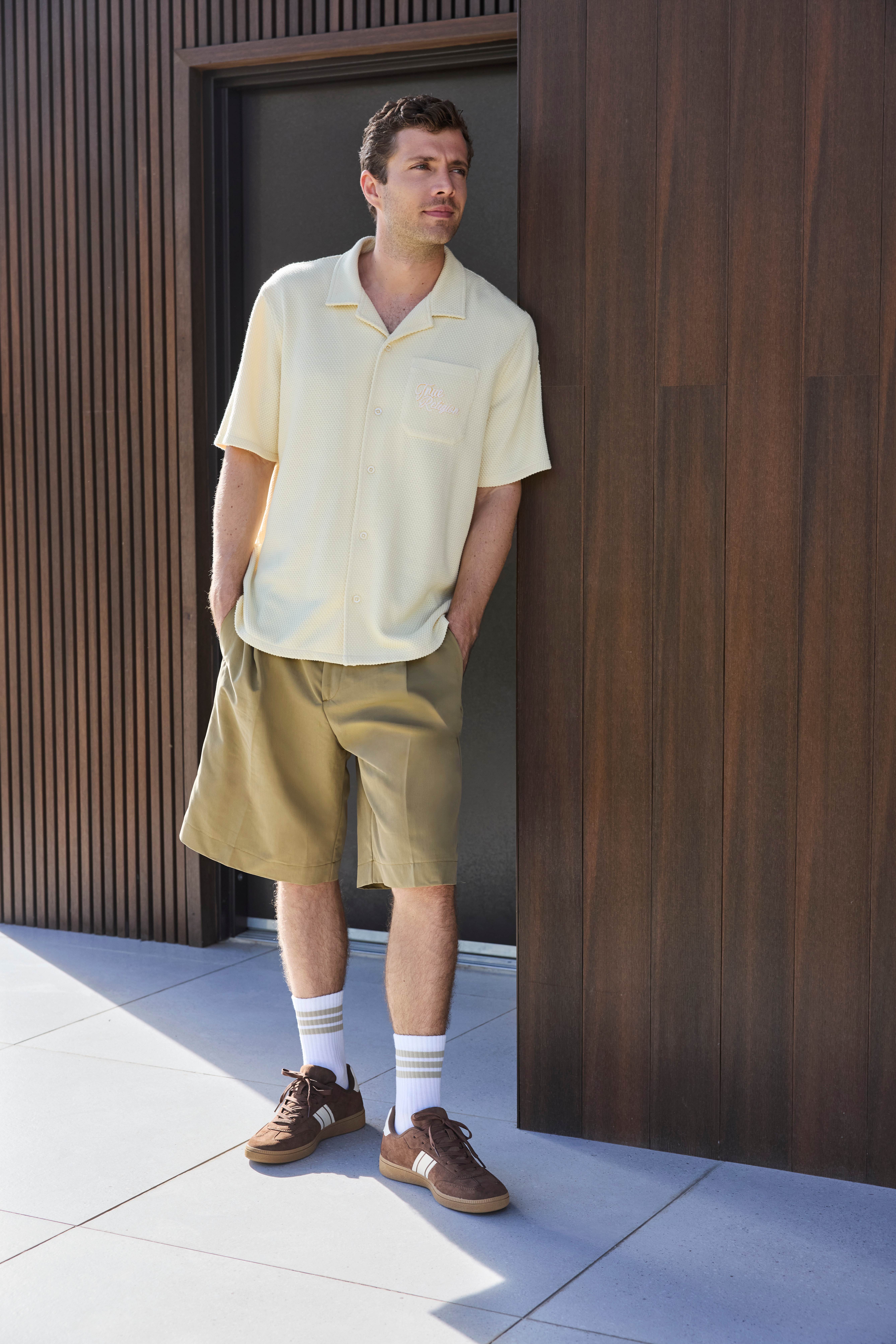 Mann in hellgelbem Hemd und brauner Cargopants