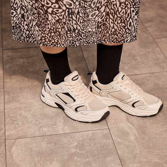 Frau trägt schwarze Socken zu weißen Sneakern