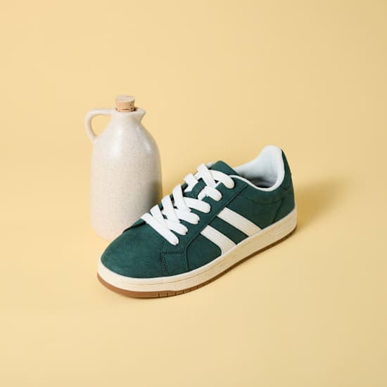 Kleine Flasche mit Essig steht neben Schuh