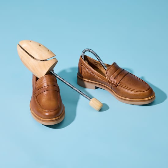 Braune Lederschuhe stehen nebeneinander, darauf lehnt ein Schuhdehner zum Weiten der Schuhe