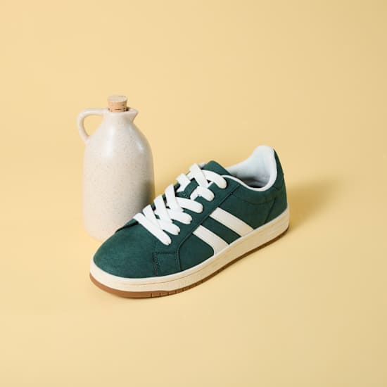 Kleine Flasche mit Essig steht neben Schuh