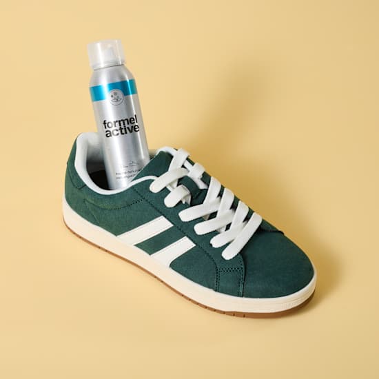Eine Dose Schuhspray steht in einem grünen Sneaker-Schuh