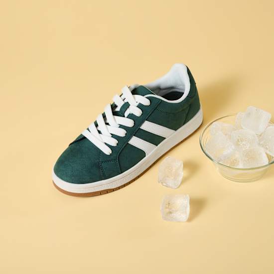Grüner Sneaker-Schuh steht neben kleiner Schüssel mit Eiswürfeln