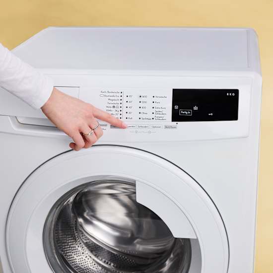 Person stellt Temperatur bei einer Waschmaschine ein