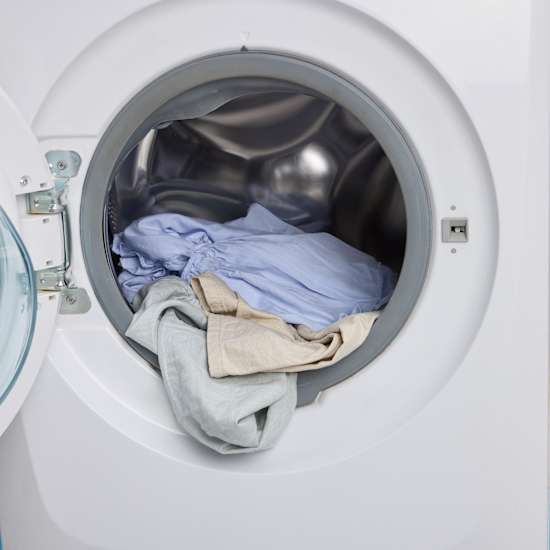 Kleidungsstücke aus Leinen liegen in Waschmaschine