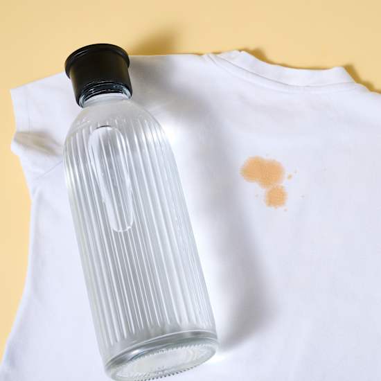 Flasche Wasser steht auf Shirt mit Kaffeeflecken