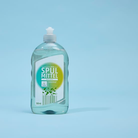 Transparente Flasche mit Spülmittel vor blauem Hintergrund
