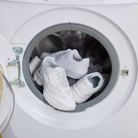 Weiße Sneaker stehen in einer Waschmaschine