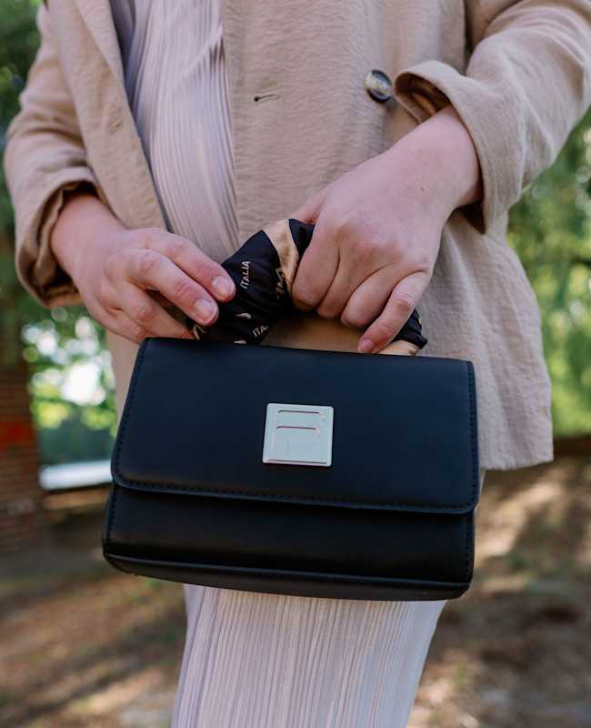 Frau trägt schwarze Fila-Handtasche in Kombination mit klassischem Blazer