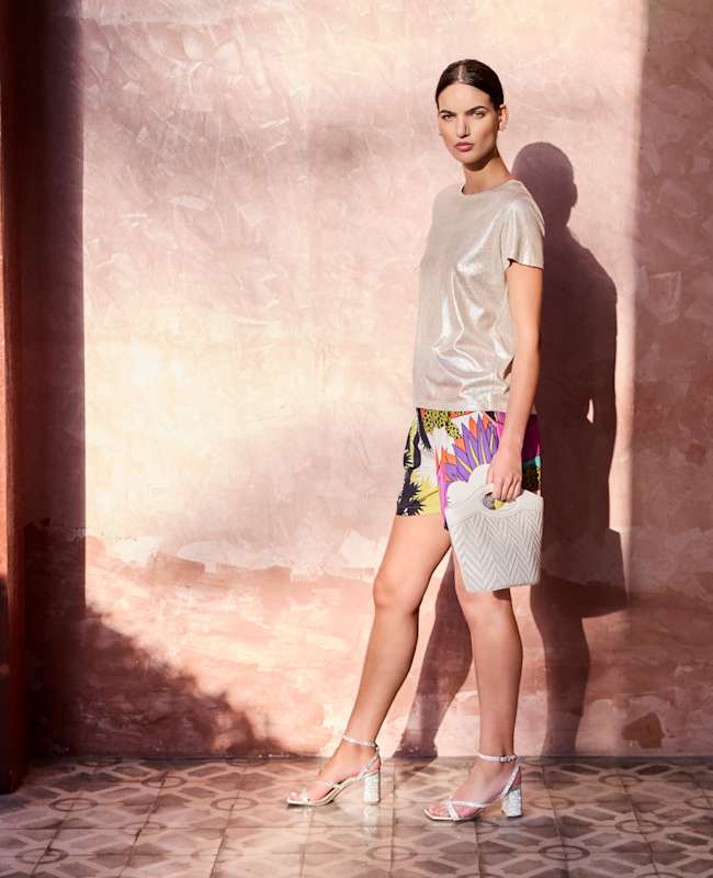 Frau mit Glitzer-Top und glitzernden Crystal-Sandaletten, kombiniert mit Minirock & Handtasche