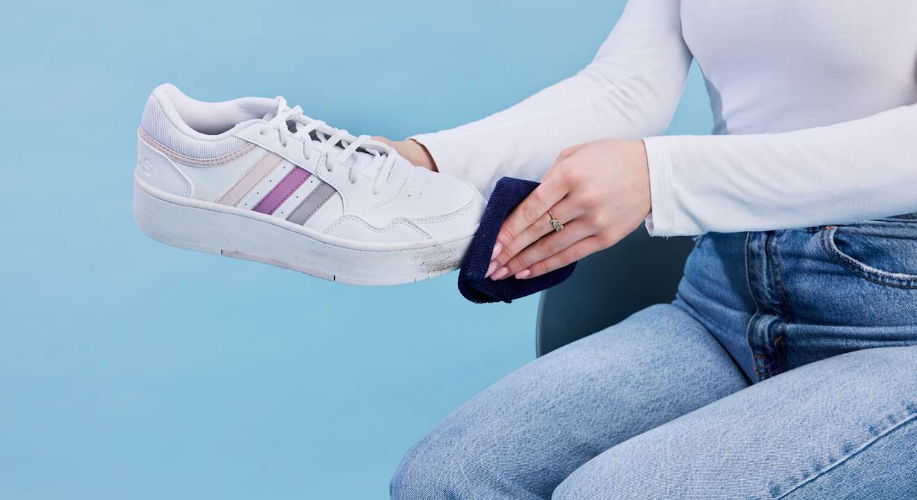 Person reinigt Sneaker mit Putztuch