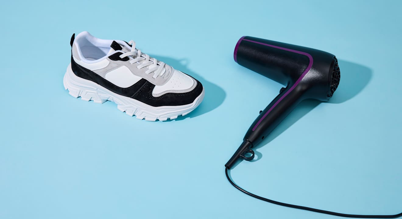 Schwarz-weißer Sneaker steht neben schwarzem Föhn