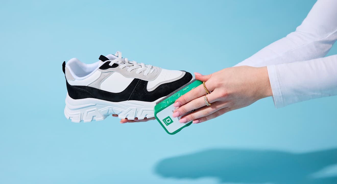 Frau behandelt Sneaker-Schuh mit Schuhschwamm