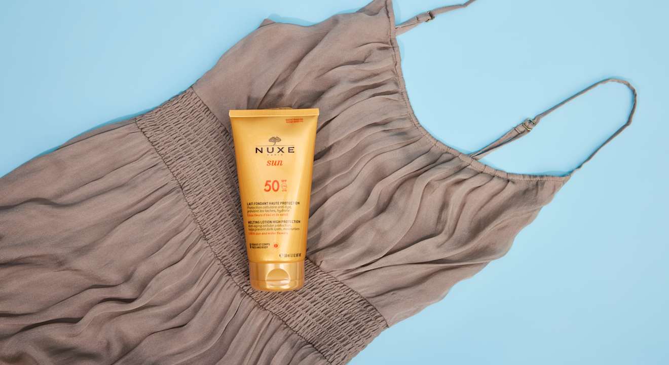 Flasche Sonnencreme liegt auf Kleidungsstück mit Flecken