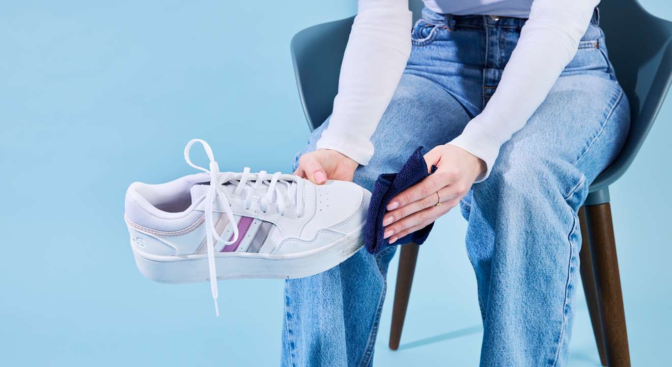 Person sitzt auf Stuhl und reinigt Sneaker-Schuh