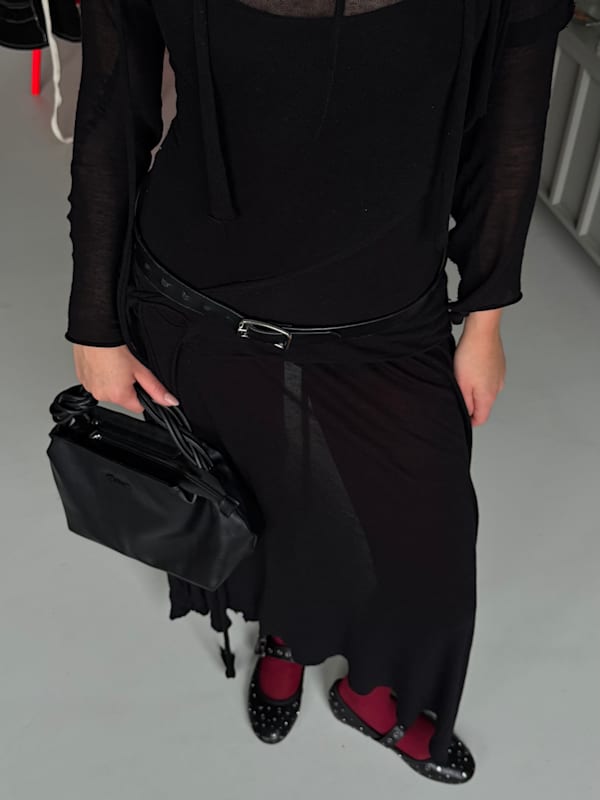 Frau in schwarzem Kleid , kombiniert mit schwarzer Handtasche und Ballettschuhen