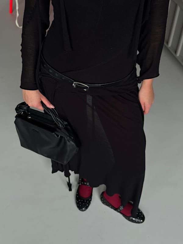 Frau in schwarzem Kleid , kombiniert mit schwarzer Handtasche und Ballettschuhen