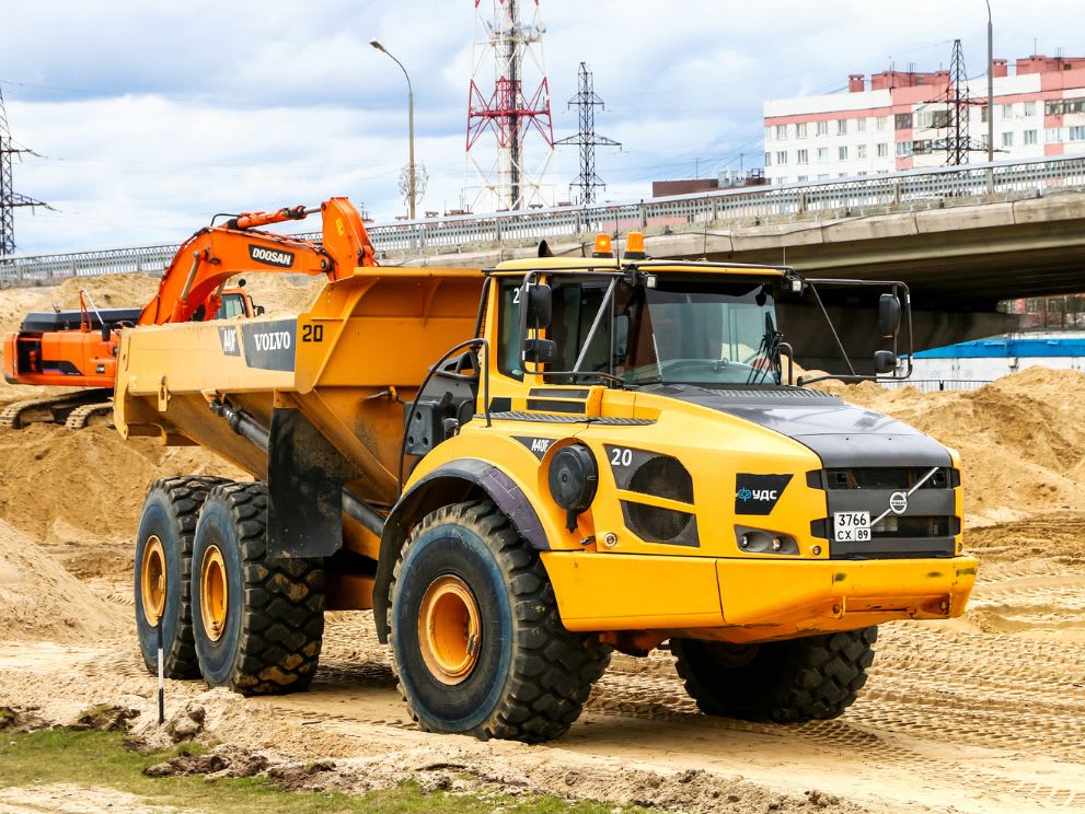 Articulated dump truck being used to haul materials away from a road construction site