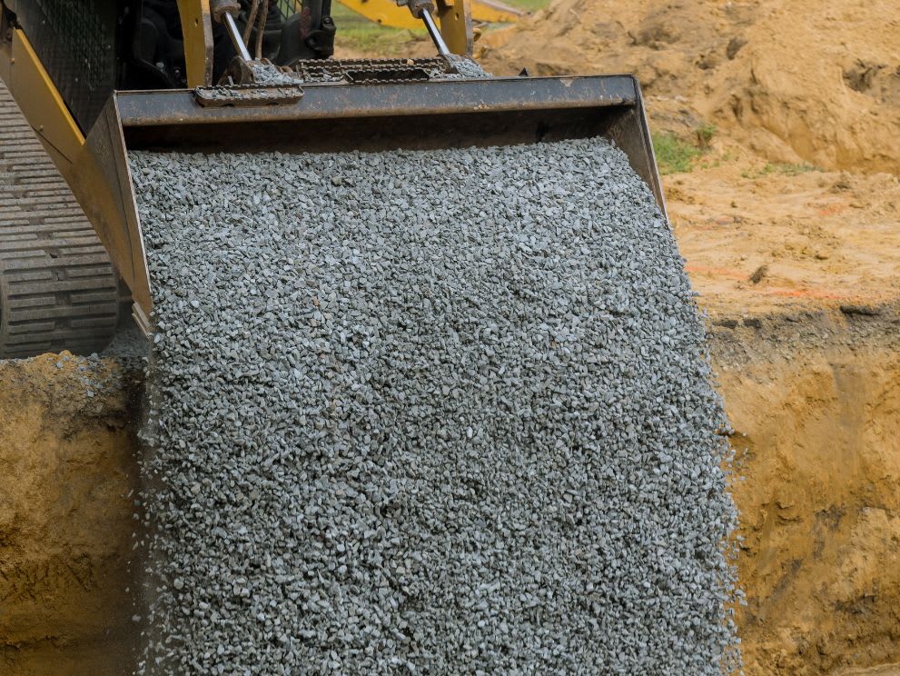 compact track loader backfilling with stone