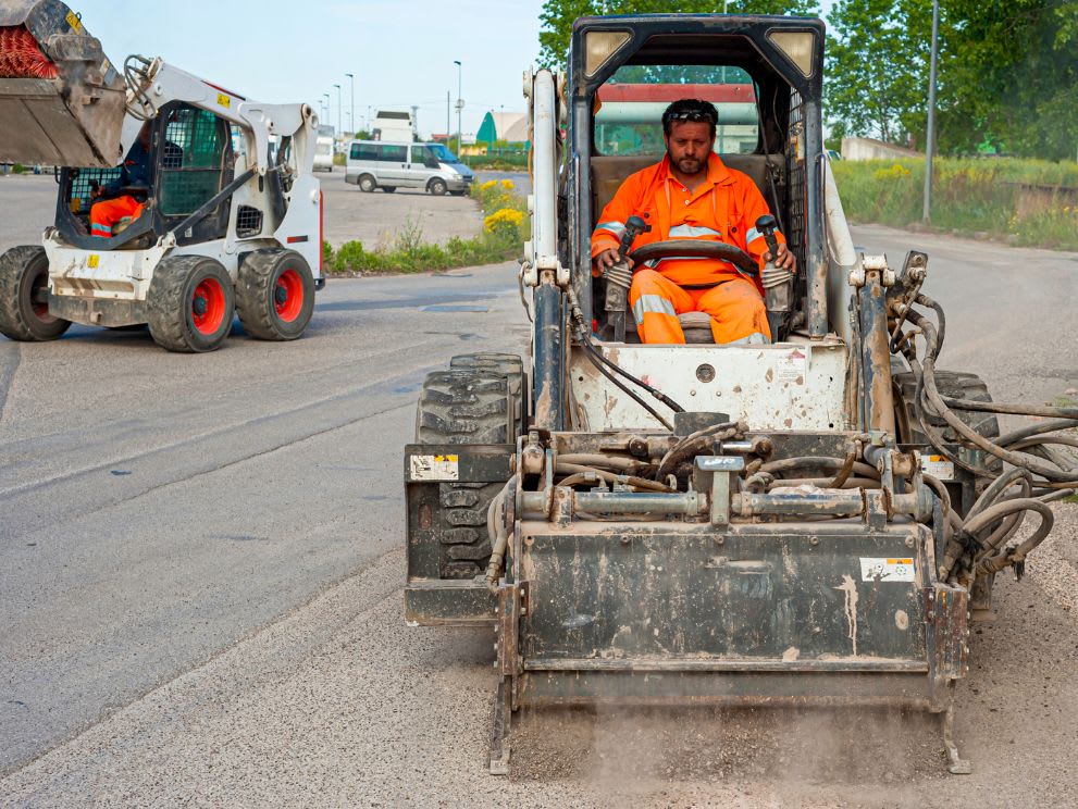 Skid steer with a cold planer attachment milling a road
