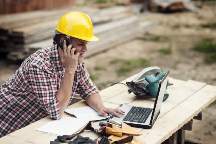 contractor looking for equipment rentals online while talking on the phone