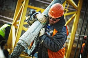 Man in PPE carrying pipe on a work site