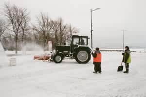 Successful winter season workers shoveling in personal protection equipment