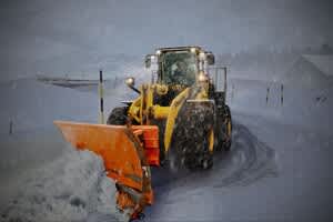 Tractor with plow attachment in snow storm.