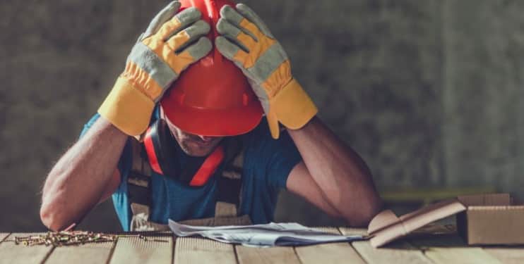 construction worker holding head with hands