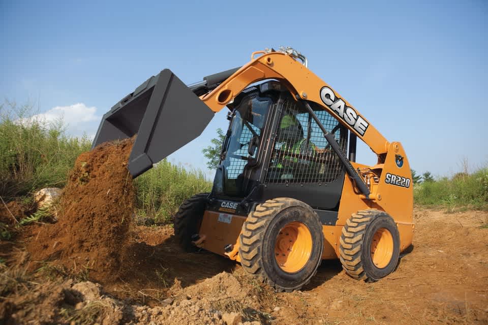 Skid steer loader dumping load of sand