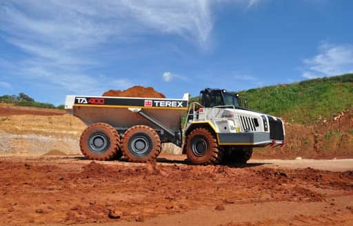 A Terex articulating dump truck driving over dirt on the construction site