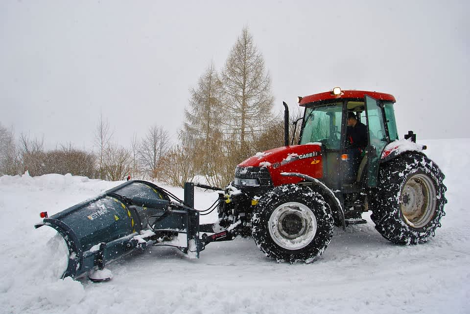 Tractor with plow attachment moving snow