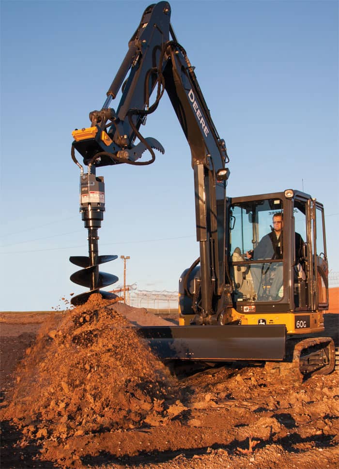 excavator with auger attachment digging hole in soil