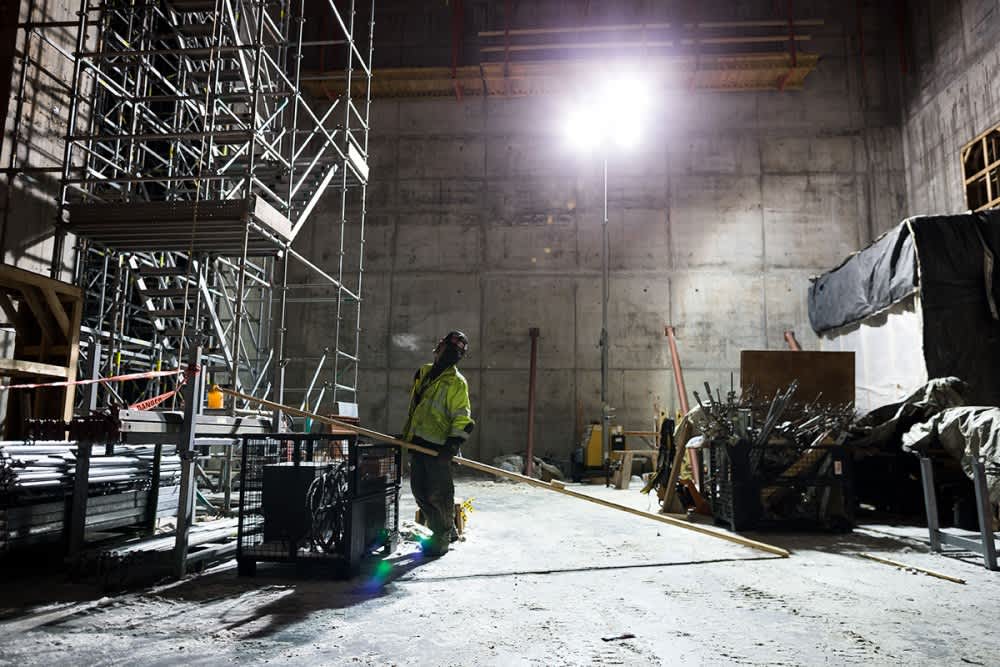 Construction worker looking up on construction site light up by tower light