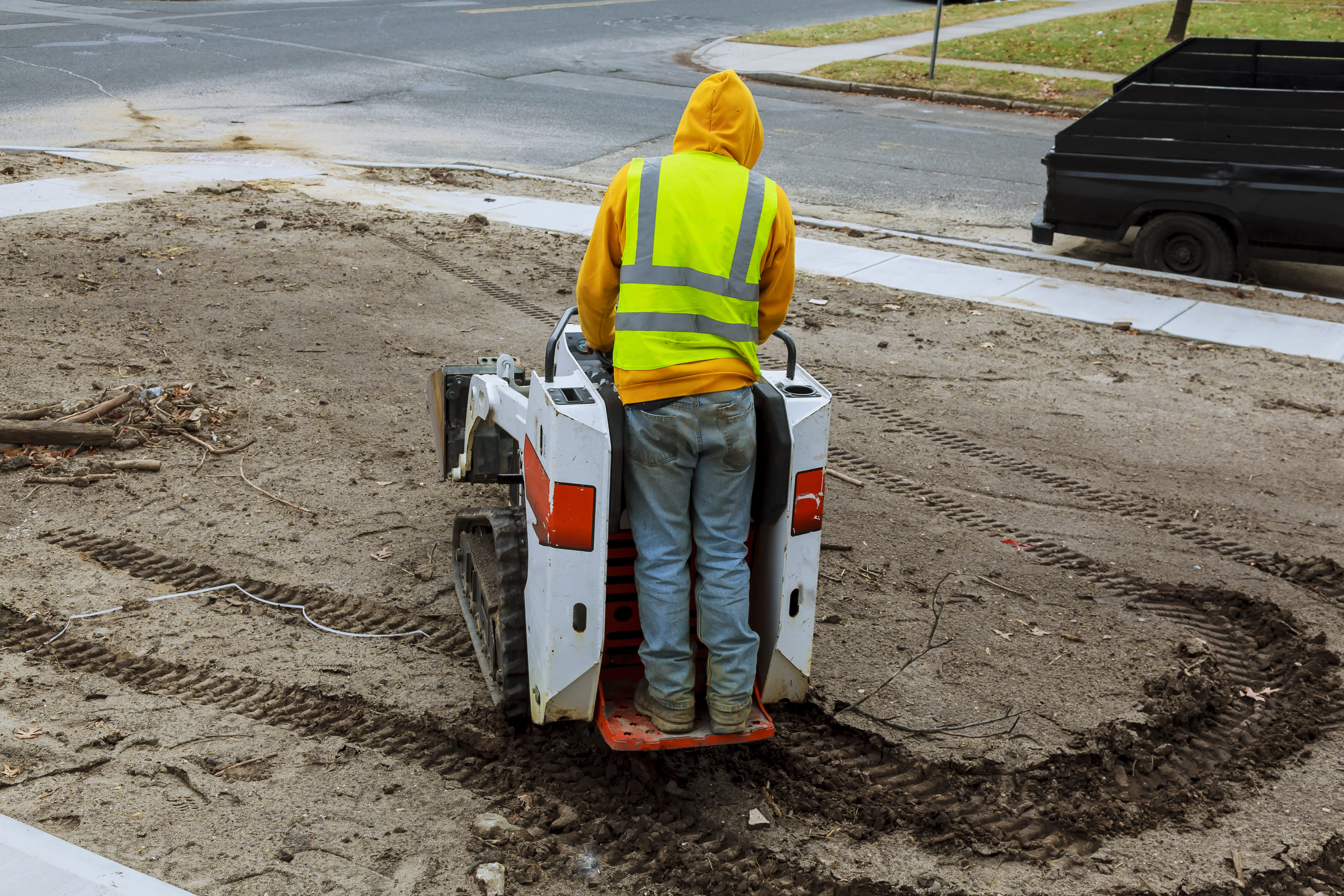 Walkbehind skid steer moving dirt on lawn