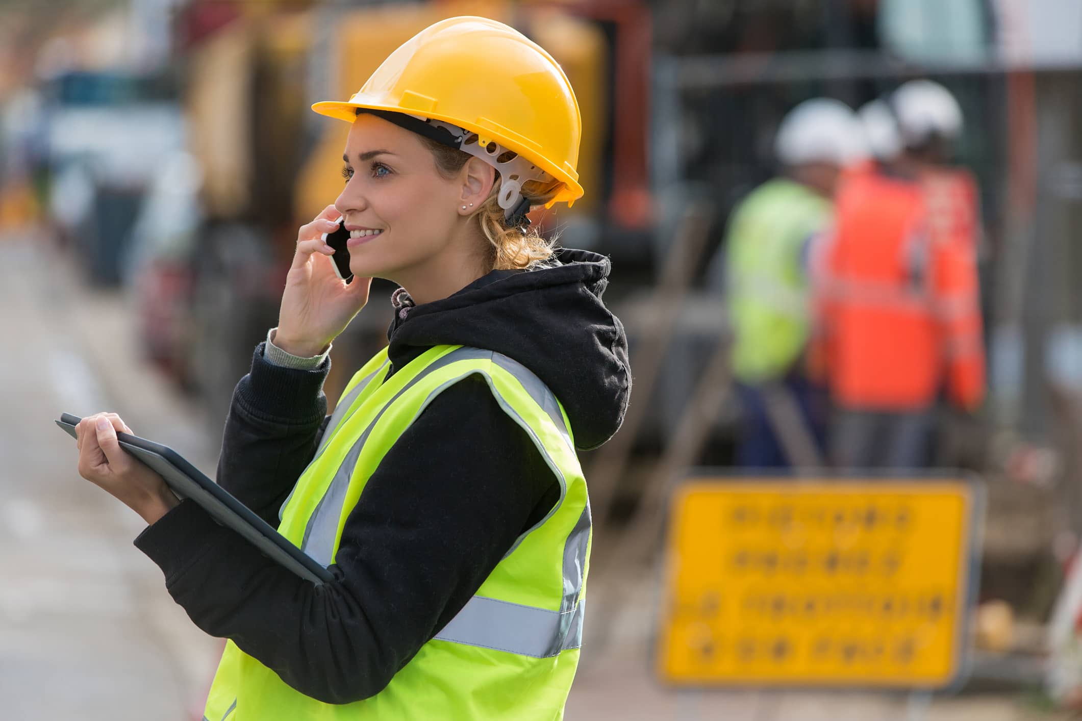 Construction worker talking on phone while holding tablet