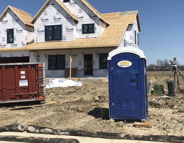 Porta potty in front of a construction project of a house