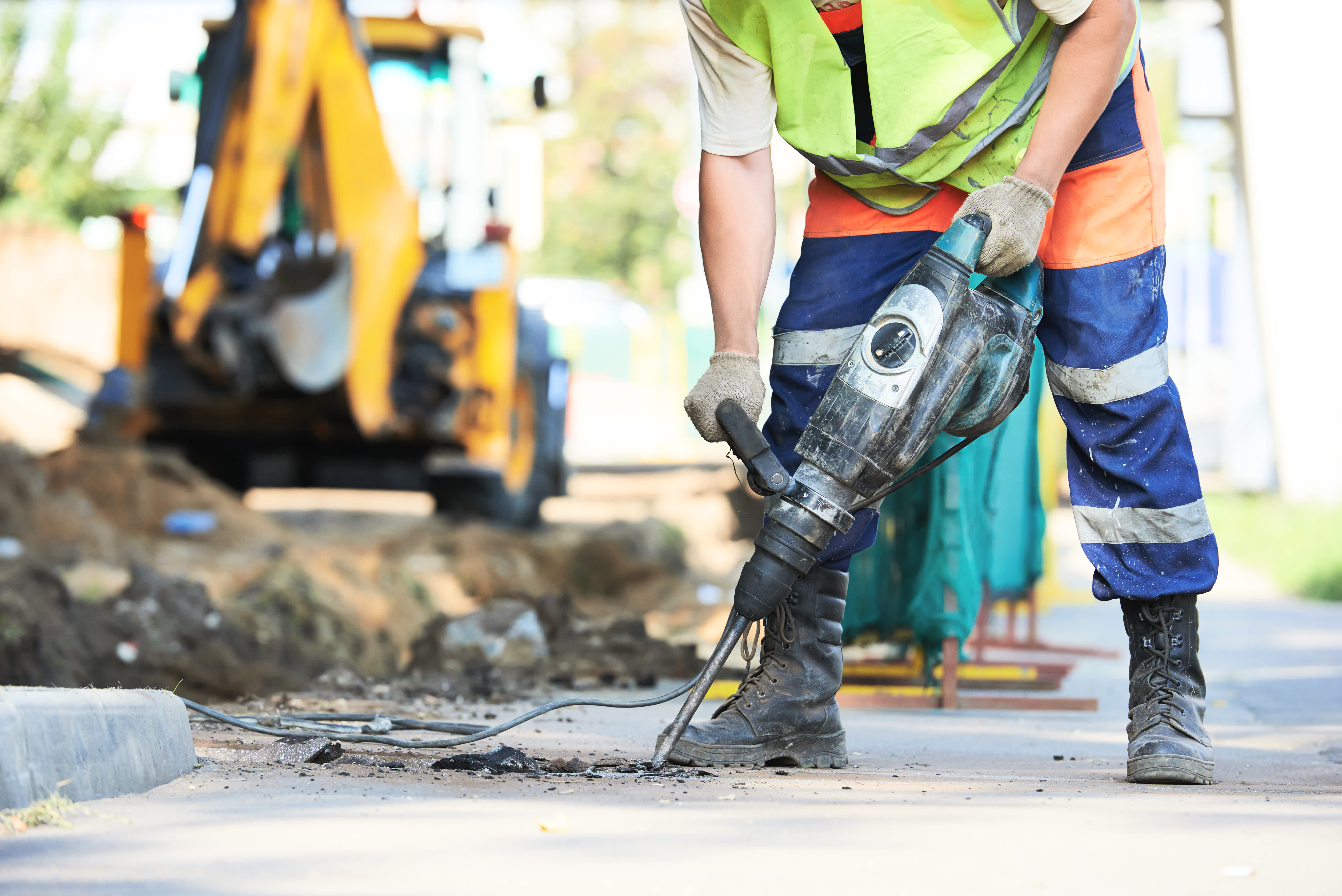 Urban city construction worker using jackhammer on city street