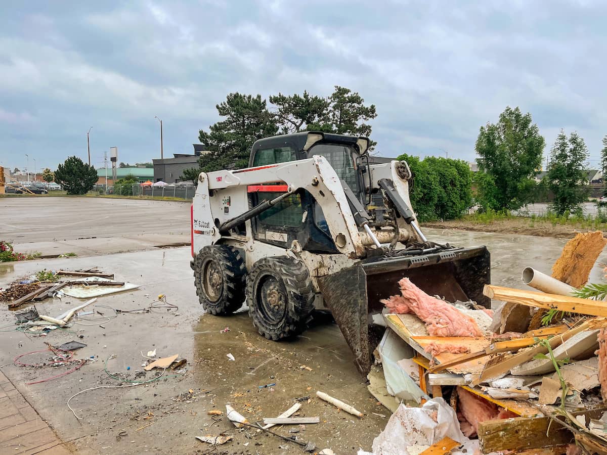 skid steer with bucket attachment moving debris