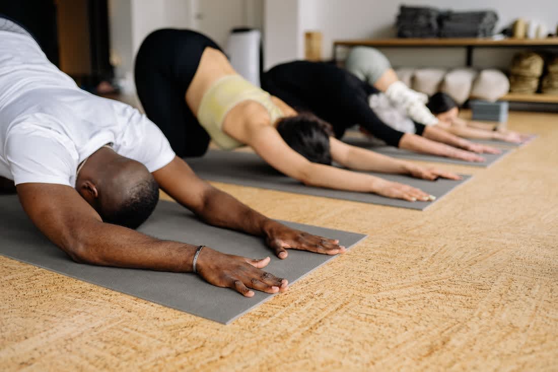 people performing downward facing dog yoga pose in a yoga class